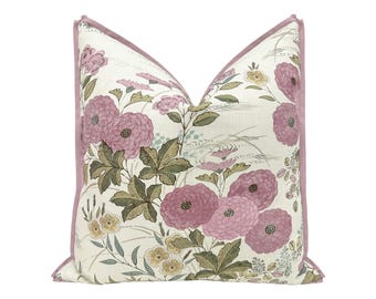 May include: A square throw cushion featuring a cream-coloured fabric base with a botanical print of mauve-pink flowers and sage-green leaves. The cushion is finished with a solid mauve-pink piped edge along the perimeter of the square shape.