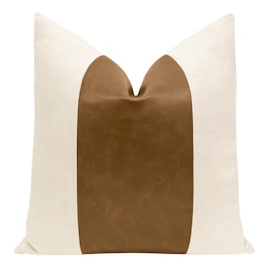May include: A white pillow with a brown leather panel down the center. The panel is shaped like a rounded rectangle.
