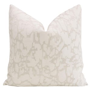 May include: A white throw pillow with a subtle, abstract pattern in a light gray color.