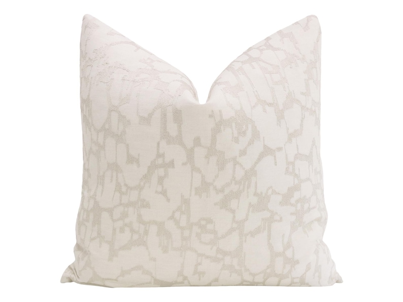 May include: A white throw pillow with a subtle, abstract pattern in a light gray color.