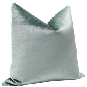May include: A light blue velvet pillow with a smooth, silky texture. The pillow is rectangular and has a slightly pointed top.