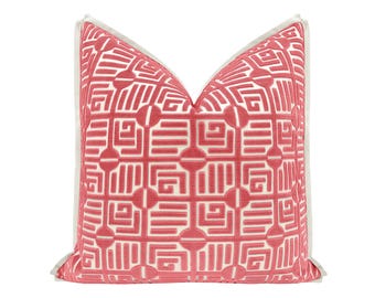 May include: A pink and white geometric patterned throw pillow with a white border.