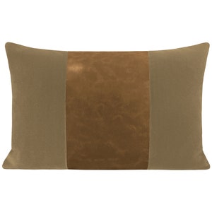 May include: A rectangular pillow with a brown leather center panel and two beige fabric side panels.