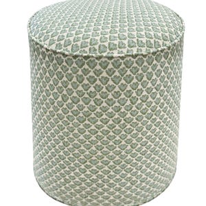Pode incluir: Um pufe cil&iacute;ndrico com um tecido estampado. O tecido apresenta um design repetido de formas verdes em forma de folha sobre um fundo creme. O pufe tem uma parte superior e inferior arredondadas e mede aproximadamente 46 cm de di&acirc;metro e 46 cm de altura.