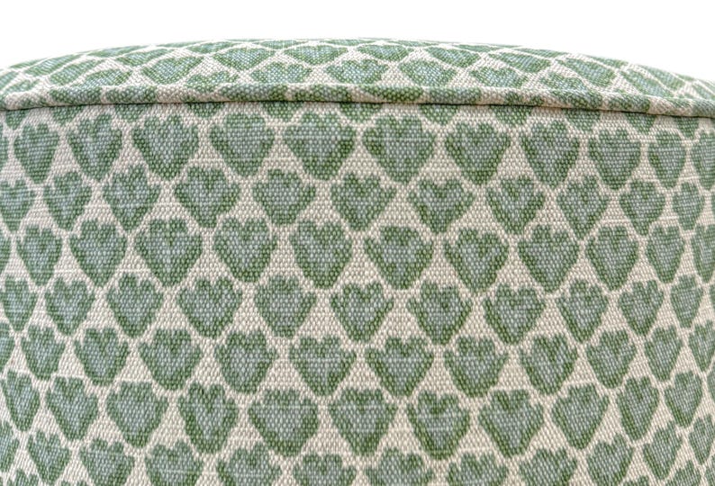 Pode incluir: Close-up de um tecido com um padr&atilde;o repetido de cora&ccedil;&otilde;es verdes sobre um fundo creme. O tecido tem uma apar&ecirc;ncia texturizada e &eacute; provavelmente usado para estofados ou decora&ccedil;&atilde;o de casa.