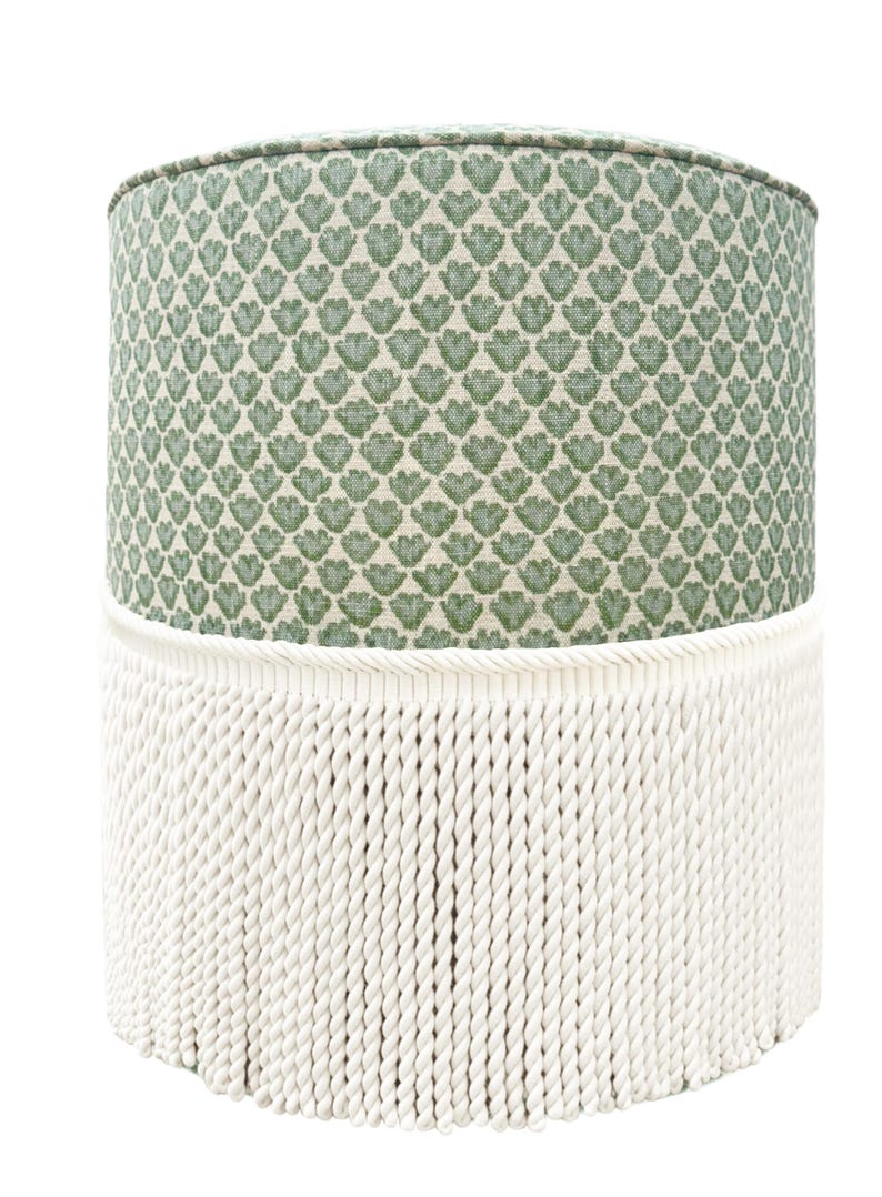 Pode incluir: Um pufe cil&iacute;ndrico com um tampo com padr&atilde;o floral verde e uma base de franjas de corda branca. O padr&atilde;o verde &eacute; um desenho repetido de folhas estilizadas. Uma pe&ccedil;a de mobili&aacute;rio decorativa.