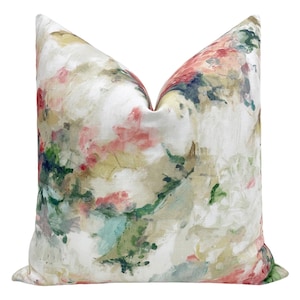 May include: A white pillow cover with an abstract floral pattern in shades of pink, green, and yellow. The pattern resembles watercolor paint splatters.