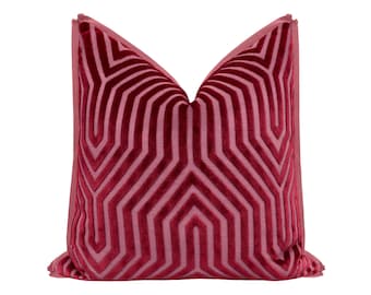 May include: A decorative throw pillow in shades of red. The pillow features a geometric pattern of lines and shapes, creating a modern design. The pillow is made of a soft, plush material, and is a square shape.