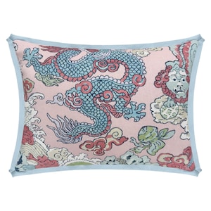 May include: Rectangular pillow with a light pink background and a detailed dragon design in teal, red, and white. The pillow has a light blue border. The dragon is surrounded by clouds and other decorative elements.