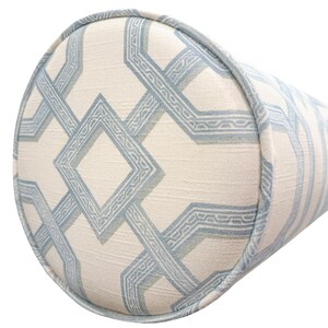 May include: A cylindrical bolster pillow featuring a cream-colored fabric base with a repeating geometric pattern in light blue. The design consists of interconnected diamond and linear shapes with a textured finish and matching blue piping trim.