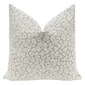 May include: A beige throw pillow with a white leopard print pattern.