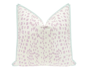 May include: A square throw pillow featuring a white base with a repeating pattern of light purple brushstroke marks. The pillow is finished with a light blue flange border along all four edges, creating a distinct frame for the patterned fabric.