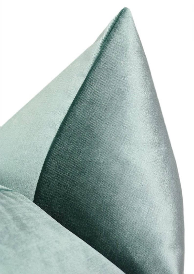 May include: A close-up of a light blue velvet pillow with a smooth, silky texture. The pillow is folded in half, showcasing the soft, luxurious fabric.