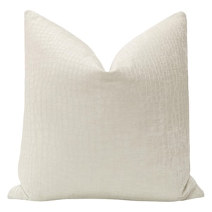 May include: A white pillow with a subtle textured pattern, resembling crocodile skin. The pillow is made of a soft, plush fabric.