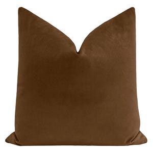 May include: A brown velvet pillow with a square shape and a smooth, soft texture.