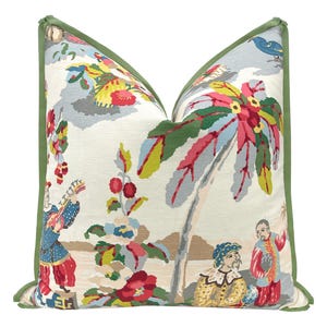 May include: A decorative pillow with a green border and a white background featuring a colorful floral and palm tree design with figures in traditional clothing.
