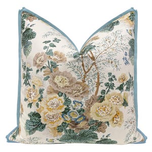 May include: A decorative pillow with a floral pattern featuring a variety of flowers in shades of brown, yellow, and green. The pillow has a light blue border.