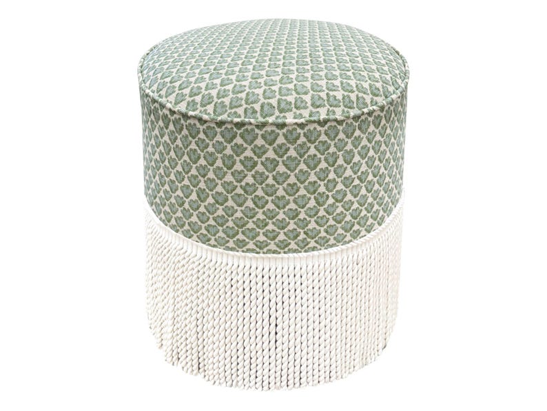 Pode incluir: Um pufe redondo com um padr&atilde;o floral verde e branco na parte superior e nas laterais. A base do pufe &eacute; adornada com uma franja branca. Uma pe&ccedil;a de mobili&aacute;rio decorativa.