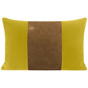 May include: A yellow throw pillow with a brown suede center panel. The pillow has a rectangular shape and is made of a soft, textured fabric.