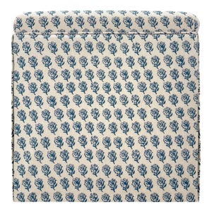 May include: A section of a cream-colored upholstered item with a repeating pattern of blue floral designs. The fabric is tightly woven, and the pattern is evenly spaced across the surface.