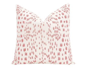 May include: A square throw pillow featuring an off-white base color with a repeating pattern of vertical, brushstroke-style marks in a muted dusty rose pink color. The pillow has a plump, filled appearance with crisp, pointed corners.