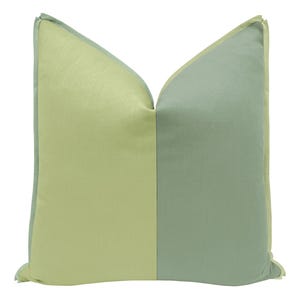 May include: A green and yellow decorative pillow with a light green border. The pillow is made of a soft, textured fabric.