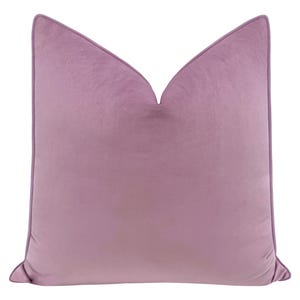 May include: A soft, plush pillow with a light purple velvet cover. The pillow has a simple, rectangular shape with a subtle pointed top.