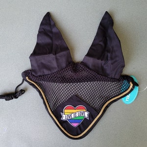May include: Black horse fly bonnet with a rainbow heart and the text "Love is Love" embroidered on it. The bonnet has a gold trim and a black mesh.