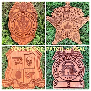 May include: Four wooden engraved badges with different designs. The top left badge is a United States Courts Probation Officer badge. The top right badge is a Sheriff's Department badge. The bottom left badge is a National Forensic Academy badge. The bottom right badge is a Georgia State Patrol badge.