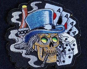 Toppa ricamata da applicare con il ferro da stiro per giacca da motociclista raffigurante un teschio fumante con cappello a cilindro, dadi e alcol.