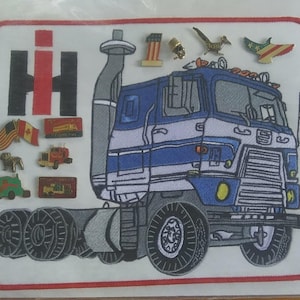 May include: A patch with a blue and white semi-truck design, the International Harvester logo, and several pins. The pins include flags, trucks, and animal figures. The patch has a red border.