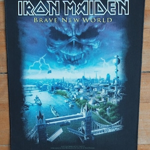May include: Black rectangular patch featuring the band name "IRON MAIDEN" in white block letters above "BRAVE NEW WORLD". The image depicts a futuristic city with a skull and lightning bolts, and the Tower Bridge. A music-themed collectible.