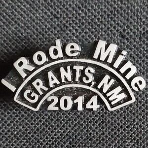 以下が含まれることがあります： 「I Rode Mine Grants, NM 2014」というテキストが湾曲した弧状に書かれた銀色のピン