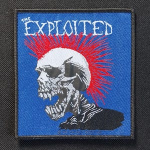 Op de afbeelding: Vierkante patch met een blauwe achtergrond met een schedel met een rode hanenkam en de tekst "THE EXPLOITED" in het wit. De schedel is gedetailleerd in zwart en wit.