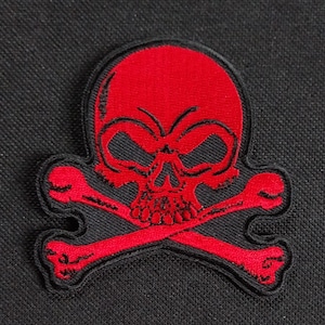 Könnte beinhalten: Gestickter Aufnäher mit einem roten Totenkopf und gekreuzten Knochen, schwarz umrandet. Der Totenkopf weist detaillierte Merkmale auf. Geeignet für Jacken, Taschen oder andere Kleidungsstücke.