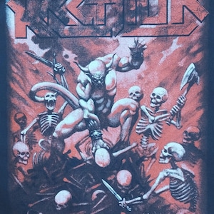 May include: Black t-shirt featuring a red and white graphic of a demonic figure and skeletons. The word "KREATOR" is at the top, with "pleasure to kill" at the bottom. The image includes the year 1985.