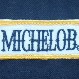 May include: A yellow and white embroidered patch with the word "MICHELOB" in black lettering.