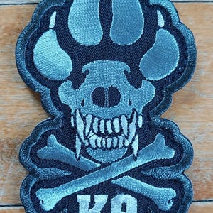 May include: A black embroidered patch with a gray paw print, skull, crossbones, and the text "K9".