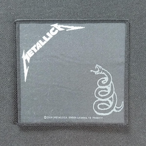 May include: Square, black patch featuring the band name "METALLICA" in white, stylized lettering. A white snake graphic is on the right. The text "©2014 METALLICA UNDER LICENSE TO PROBITY" is printed at the bottom.