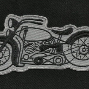 May include: A gray embroidered patch of a motorcycle with a detailed design. The motorcycle has a front wheel, a back wheel, and a detailed engine.