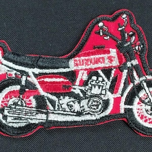Puede incluir: Parche de motocicleta bordado en rojo y negro con la palabra "Suzuki" en el lateral.