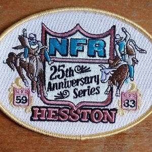 Op de afbeelding: Een witte ovale geborduurde patch met een bruin en blauw beeld van twee cowboys die op stieren rijden. De patch heeft de tekst "NFR 25th Anniversary Series Hesston" en de nummers "59" en "33" in de onderste hoeken.