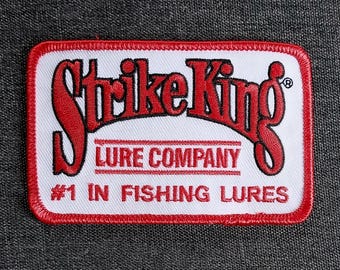 May include: Red and white embroidered patch with the text "Strike King Lure Company #1 in Fishing Lures".