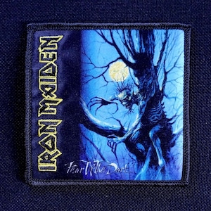May include: Square patch featuring the band name "Iron Maiden" in gold lettering. The image depicts a ghoulish figure in a tree under a full moon, with the words "Fear of the Dark" below.