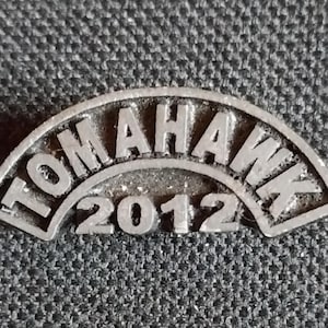 May include: A silver metal pin with the word "TOMAHAWK" arched over the year "2012".