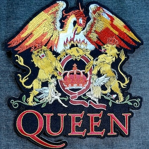 Puede incluir: Parche bordado con el escudo de Queen. El diseño incluye un fénix, leones, una corona y la palabra "QUEEN" en rojo. El parche tiene un fondo negro con detalles dorados, rojos y blancos.