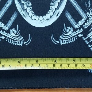 May include: Black rectangular patch with a white graphic of a skull, crossed swords, and bird talons. The patch is approximately 7 inches wide. A yellow measuring tape is placed across the bottom of the patch.