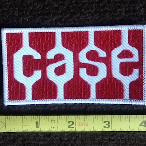 May include: Red and white embroidered patch with the word "case" in white letters on a red background.