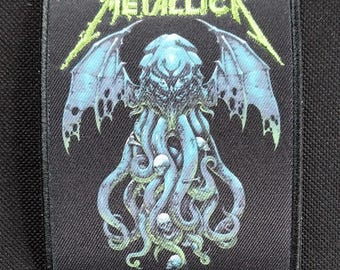 May include: Black rectangular patch featuring the band name "METALLICA" in green and a blue Cthulhu-inspired design. The design includes tentacles, skulls, and wings. The text "THE CALL OF KTULU" is at the bottom.