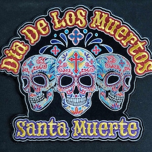 May include: A colorful embroidered patch with three sugar skulls and the text "Dia de los Muertos Santa Muerte".